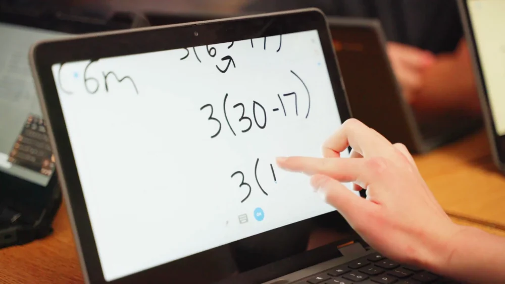 A student tracing 3(30 - 17) across a Chromebook touchscreen in their own handwriting.